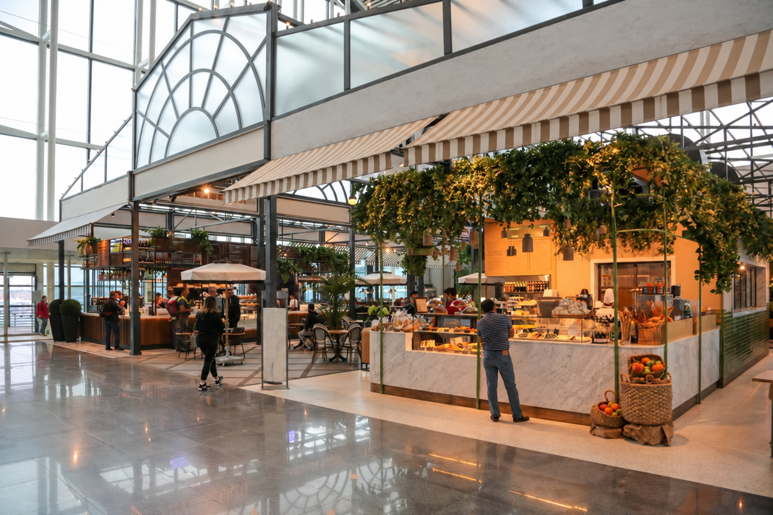 Airport concourse with dining concessions, café seating, greenery and large windows.