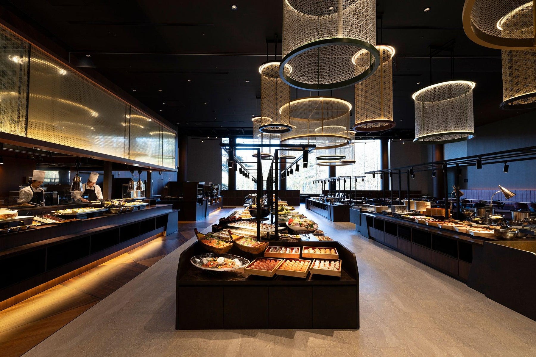 Asian buffet dining space with multiple food-service stations and suspended circular light fixtures.