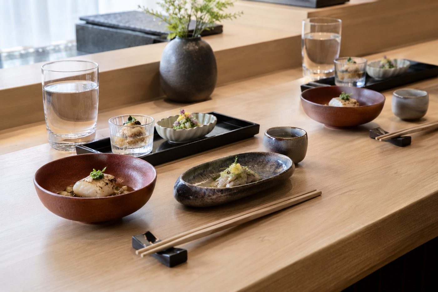 Tactile small course vessels, lacquer and glass at a contemporary omakase counter