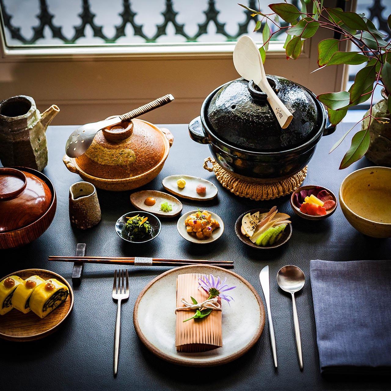 Tabletop arrangement of ceramic plates, bowls, cutlery and serving dishes.