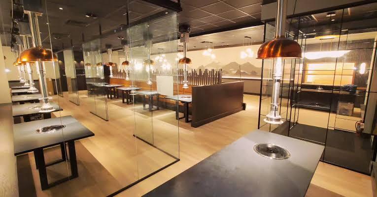 Grill tables with overhead exhaust hoods in a restaurant dining room
