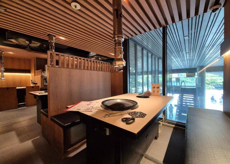 Restaurant dining room with tabletop grills and overhead exhaust hoods