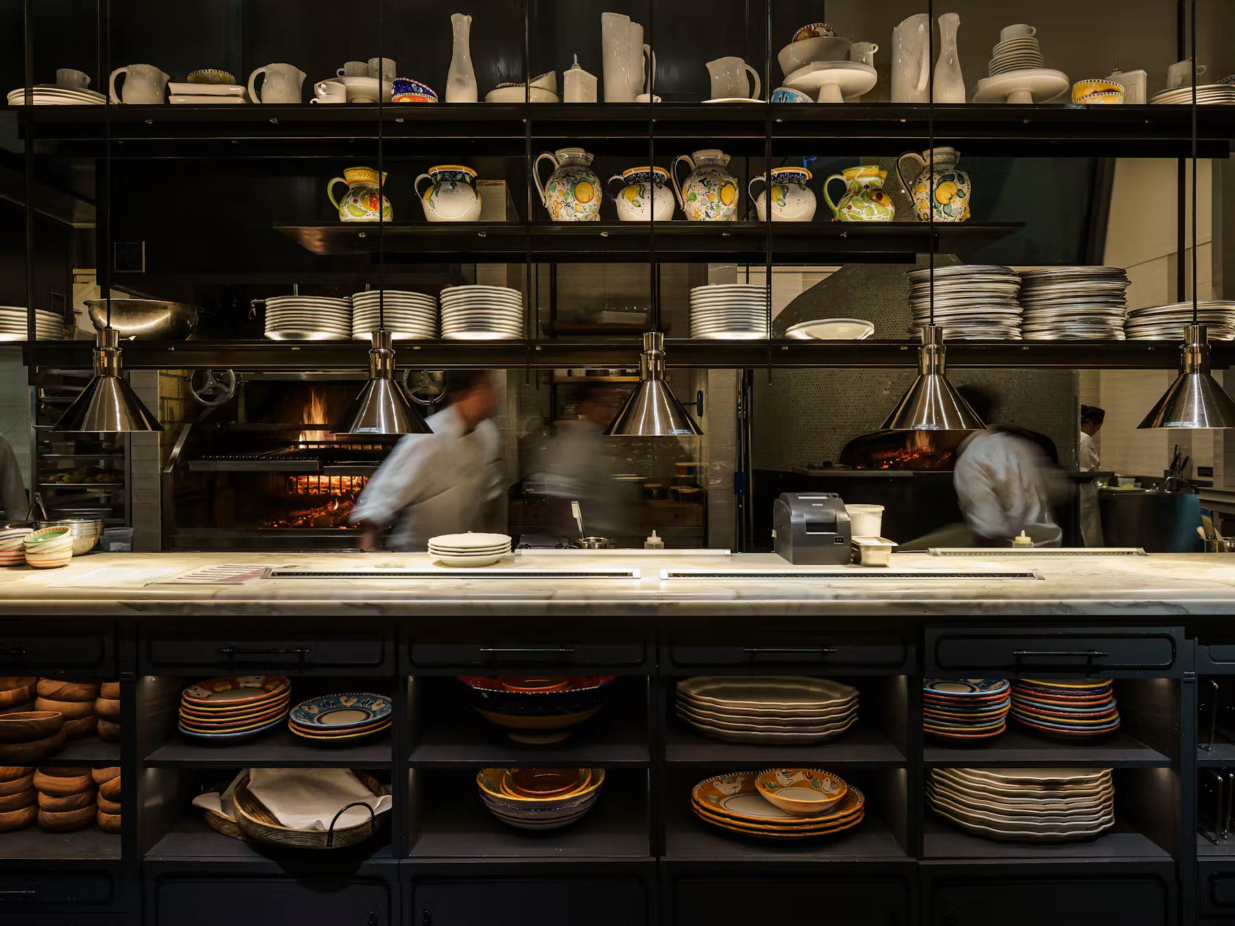 Restaurant service counter with stacks of plates, bowls and serving dishes above and below the pass.