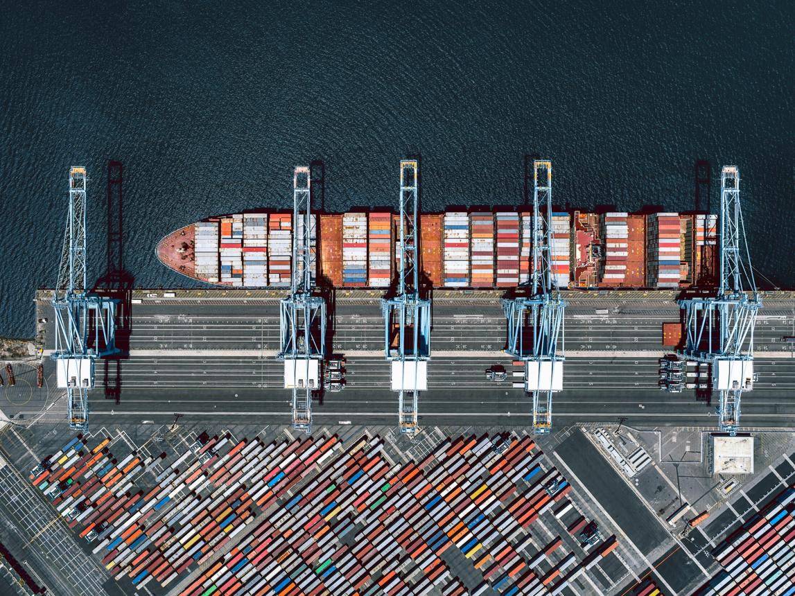 Aerial view of a container ship, port cranes and shipping containers.