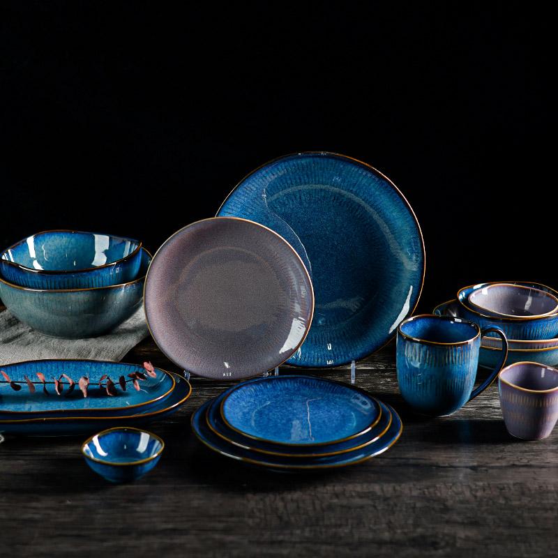 Blue mineral-toned plates, bowls and cups grouped together against a dark background.