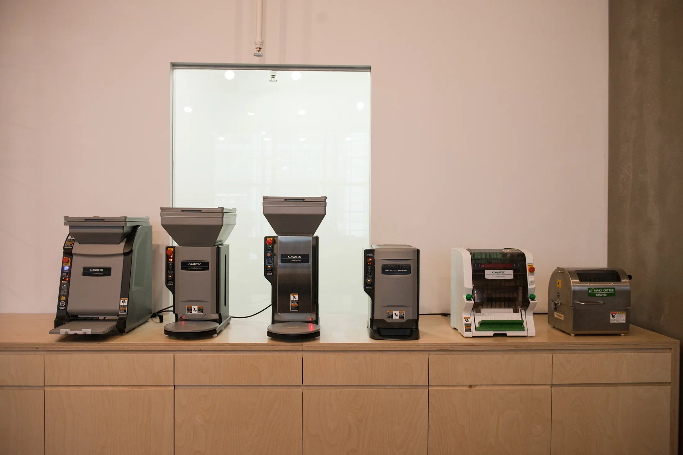 Six commercial sushi-production machines displayed on a countertop